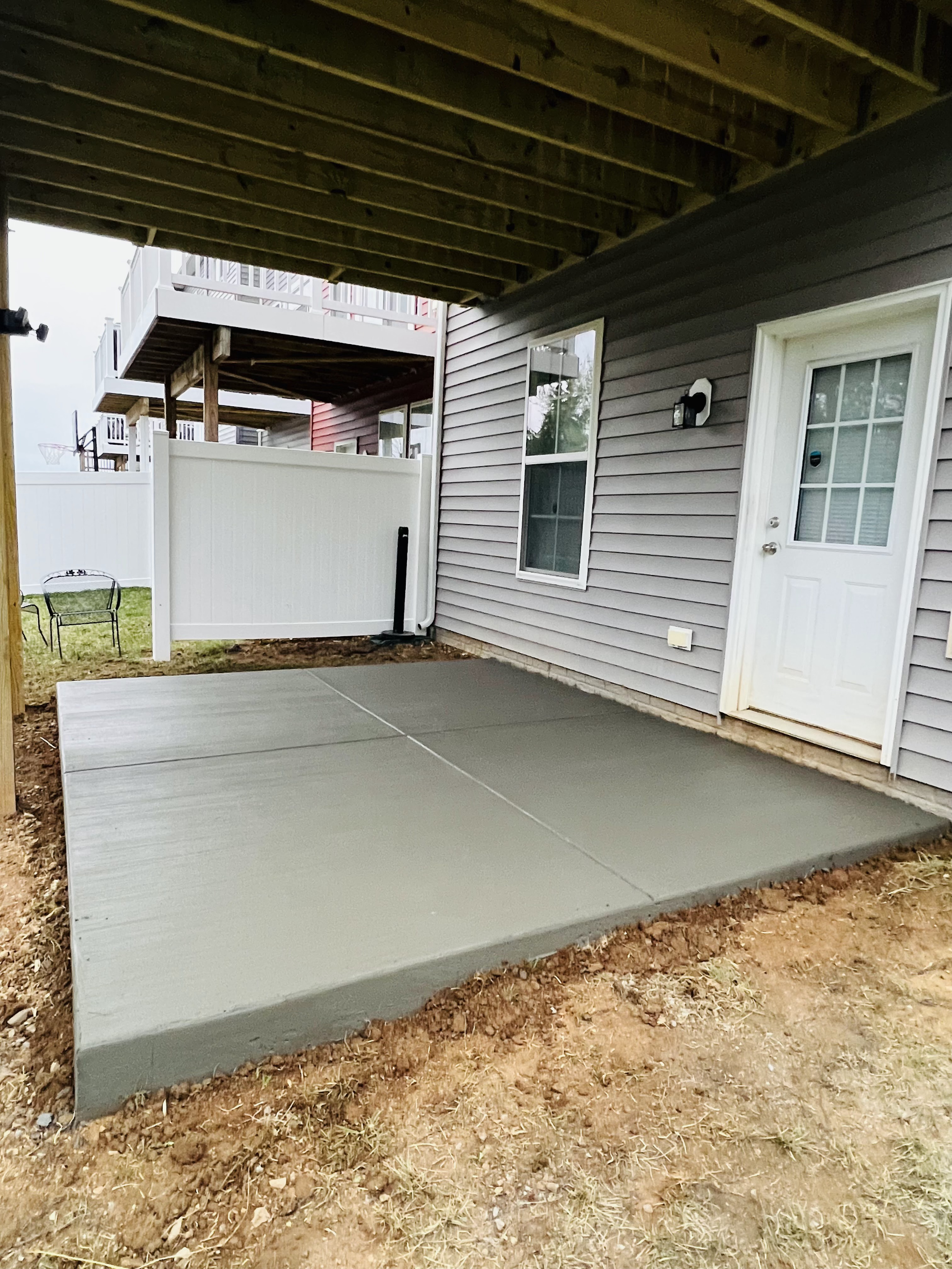 New concrete patio beneath an elevated deck